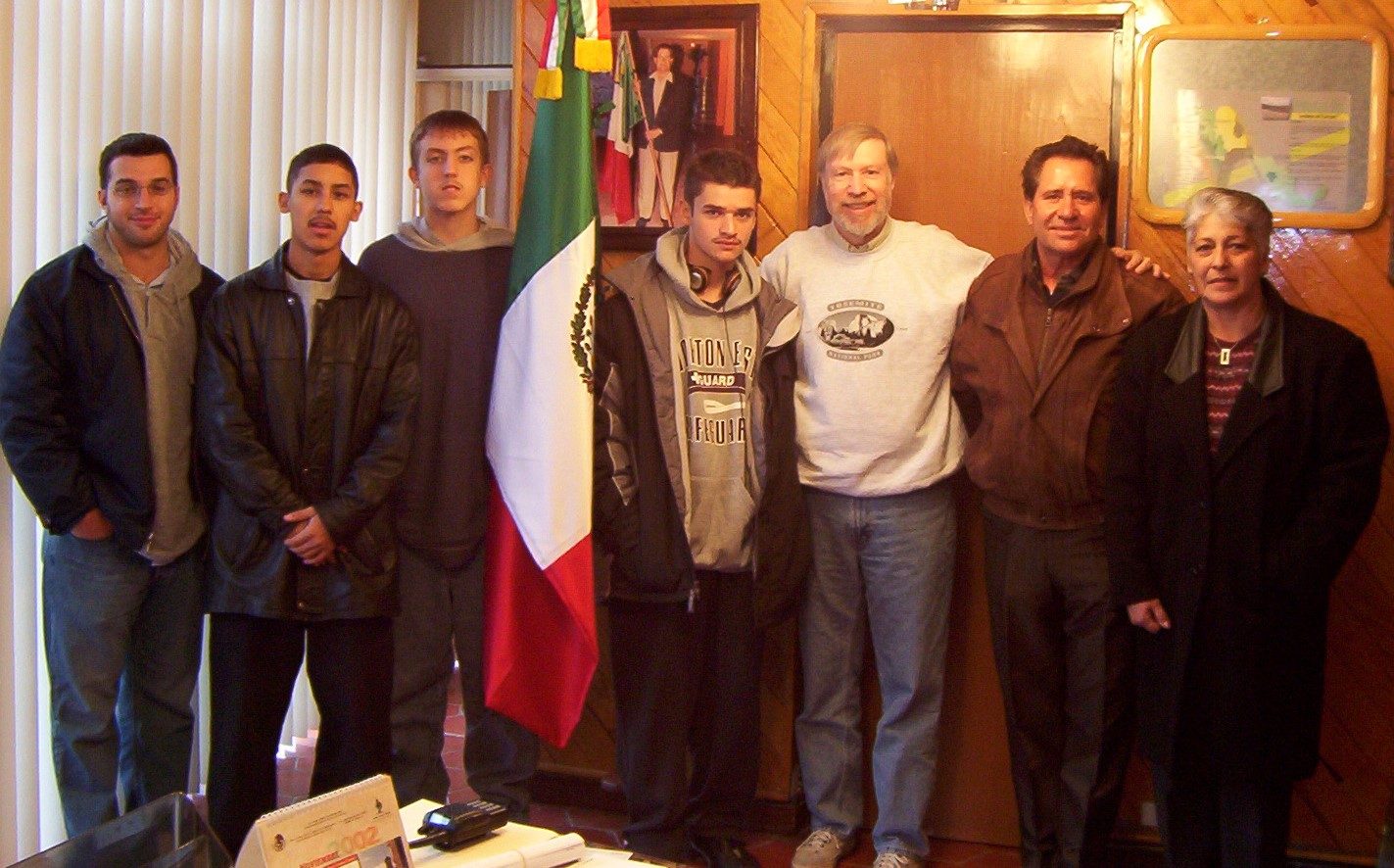 Students and adults posed in a wood-panelled office with a Mexican flag